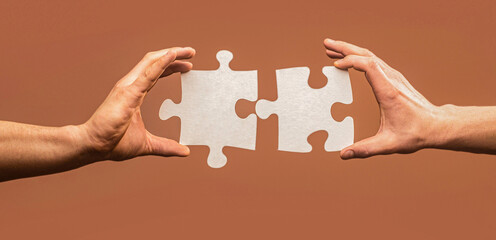 Hand connecting jigsaw puzzle. Man hands connecting couple puzzle piece. Closeup hands of man connecting jigsaw puzzle. Two hands trying to connect couple puzzle
