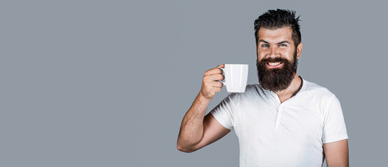 Smiling bearded hipster man holding cup of coffee or tea. Handsome mans holds cup of coffee, tea. Bearded man smiling. Good morning, man tea. Smiling hipster man with cup of fresh coffee, happy man