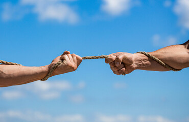 Hand holding a rope, climbing rope, strength and determination. Rescue, help, helping gesture or hands. Conflict, tug of war. Two hands, helping hand, arm, friendship.