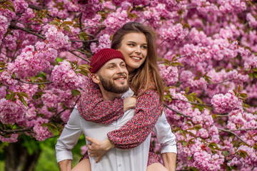 Lovers couple hugging in a sakura. Love, youth, happiness concept. Couple in love outdoor. Sensual outdoor portrait of young stylish fashion couple. Couple lovers hugging in the park
