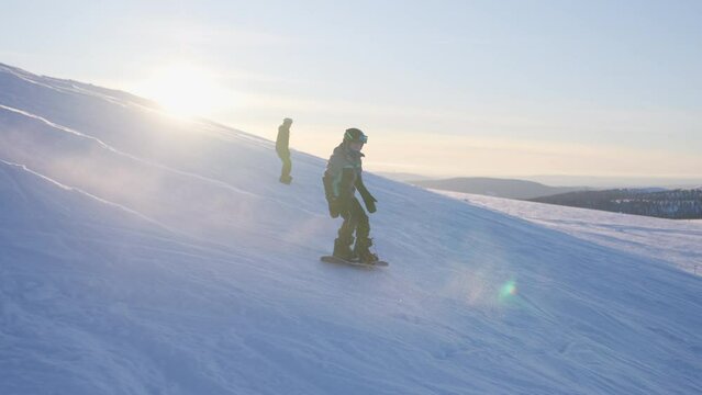 Kids' Dynamic Downhill Snowboarding Amidst Glowing Sun