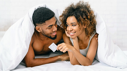 Young couple is smiling and holding condom