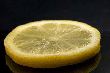 Macro detail of fresh yellow lemon slice split with black background horizontal