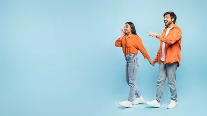 Fototapeten Couple pointing to side and looking surprised © Prostock-studio