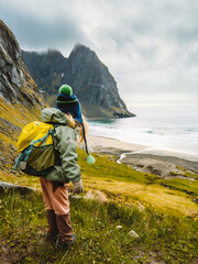 Child backpacker hiking in Lofoten islands travel family vacations outdoor active healthy lifestyle 4 years old kid with backpack enjoying Kvalvika beach ocean view in Norway adventure trip