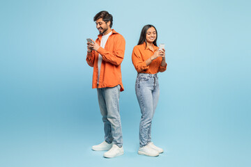 Couple using smartphones back to back on blue background