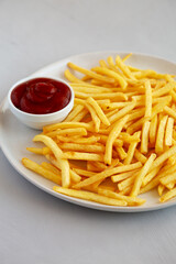Fried French Fries with Ketchup on a Plate, side view.