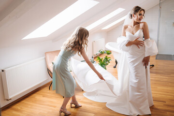 Morning of beautiful bride with her youngest sister. Bridesmaid helping to bride dress her wedding dress. Retro hotel with brick wall