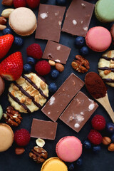 Macarons, chocolate, cookies, berries and various nuts on dark blue background. Top view.