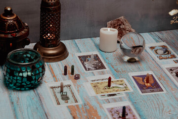 A dimly lit scene showing a spread of tarot cards, alongside crystals, candles, and a crystal ball...