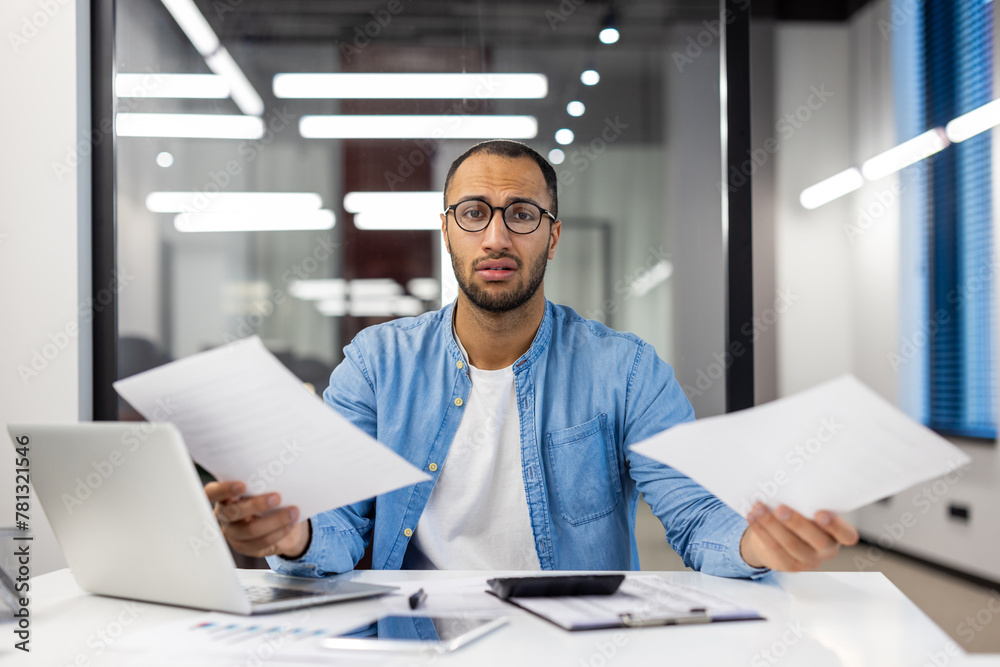 Wall mural confused businessman analyzing paperwork in modern office