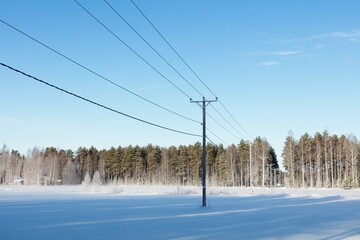 Power lines in clear winter weather with snow on the ground, Loppi, Finland.