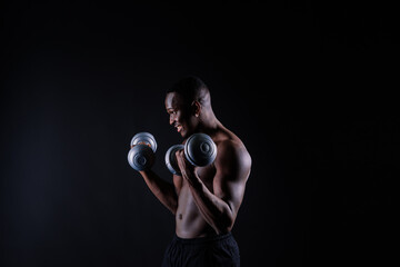 Young man with dumbbells good physique isolated on red and black background. Strength and motivation