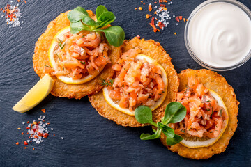 Crispy potato pancakes with salted salmon and sour cream. Top view