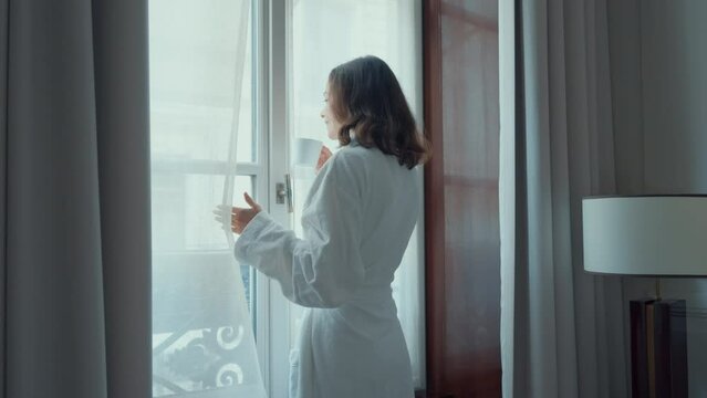 Woman in Bathrobe Enjoying Coffee by Hotel Window