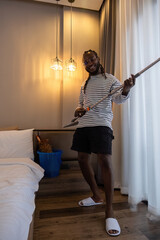 Playful African man in casual clothes Clean the dust or dirtiness of the room happily and have fun cleaning.