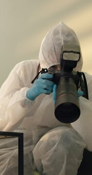 Person, home and forensic photographer for evidence at crime of burglary, investigation or examination. Ppe suit, camera and pictures in living room for homicide case research, accident or csi