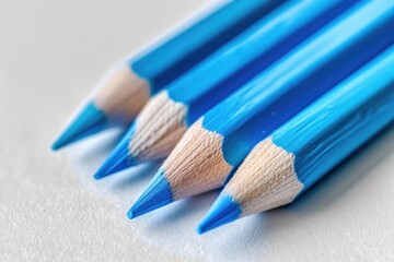 A row of four blue pencils with a blue tip. The pencils are placed on a white surface - Powered by Adobe