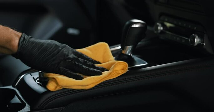 car interior cleaning. hand with microfiber cloth cleans center console