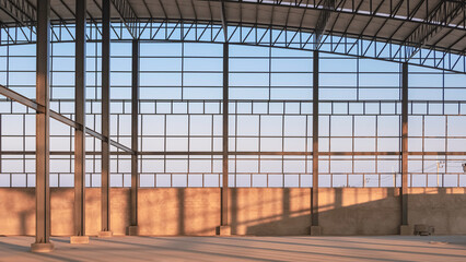 Steel wall framework structure with metal columns and curve roof inside of large industrial factory building in construction site area with evening sunlight and shadow on concrete floor