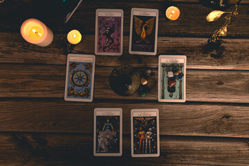 Tarot cards including The Fool and The Lovers alongside crystals and candles on a textured wooden table.