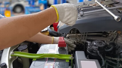 Professional car mechanic in service is checking engine lubricant, repairing faulty engine parts. - obrazy, fototapety, plakaty