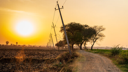 Beautiful sunset sky with electric line in the village road