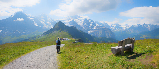 hiker at hiking way Mannlichen mountain, with view to Eiger, Monch and Jungfrau, switzerland. - obrazy, fototapety, plakaty