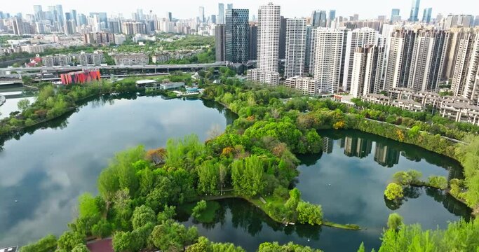 Aerial Cityscape of Chengdu at spring day in the Donghu park with fresh green trees by the riverside woods. new haigh reidential building near the park
