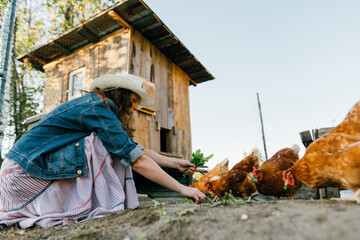Rural scene, female farmer distributing fresh greens to her chickens, organic feed. Smiling woman happily cares for her chickens, organic farm maintenance, country life