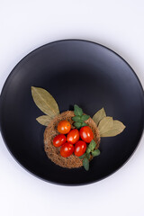 Tomatinho cereja  em cima de uma prato preto com fundo claro
