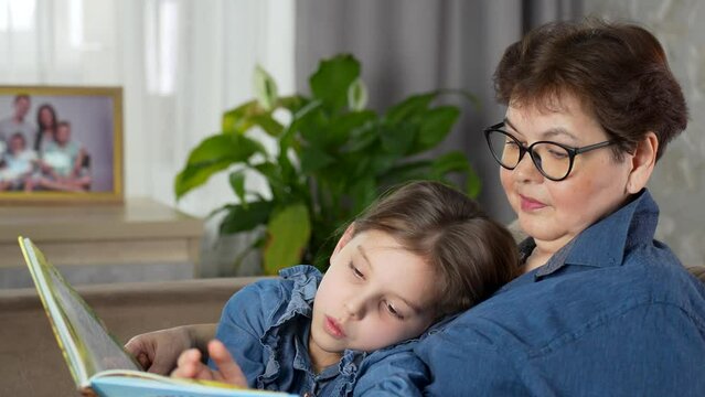 Portrait of 60 years old grandmother with her little grandchild, reading book