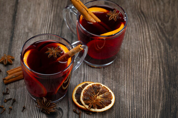 Glass of mulled wine with orange slice. Mulled wine and ingredients on a wooden table.