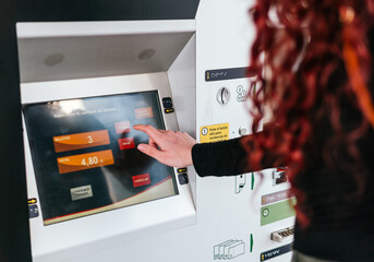 Detail of girl buying tickets for public transport at a ticket machine, touch screen