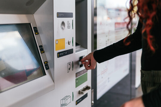 Close-up of woman inserting payment card into public transport ticket purchasing machine