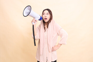 Candid Asian woman, tilted to the right, holding her waist and carrying a megaphone (loudspeaker) shouting to announce shopping promotions. beautiful women for business, technology, fashion