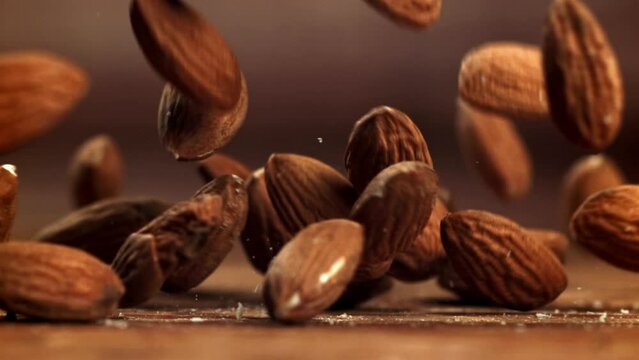 Almonds, a natural ingredient, are cascading onto a wooden table. This closeup, macro photography showcases the nuts in their shell, portraying a still life of natural foods