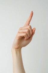 A person's index finger pointing up in the air against a white backgrop