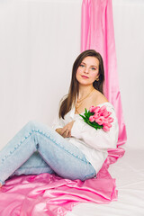 Cute and trendy spring photoshoot of a woman holding flowers with pink background. Modern, creative, cute.