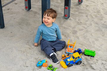 child toddler male playing on playground in sand with toys