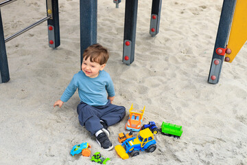 child toddler male playing on playground in sand with toys
