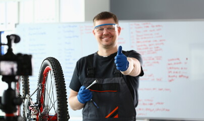 Bicycle repairman in workshop holding thumbs up. Quality bike repair concept
