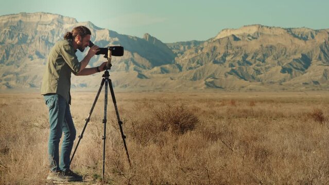 Man using telescope for bird and animal watching in nature.