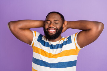 Photo of funny dreamy man wear striped t-shirt closed eyes arms behind head isolated violet color...