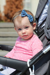 Cute little child sitting in a baby stroller on a walk