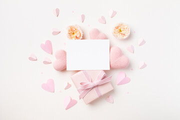 Festive background for Birthday, Woman or Mothers Day. Empty paper card, hearts, rose flowers and gift box on white table top view. - 781382512
