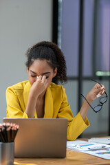 Distressed young businesswoman feeling pressure and headache at her office desk with laptop and...