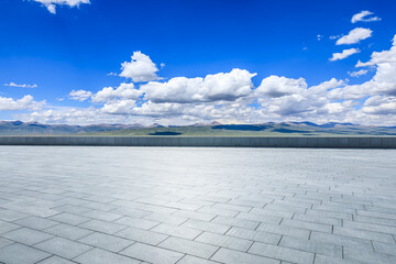 Empty square floor and mountains with sky clouds on a sunny day