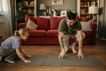 Young father and his little girl preparing a mat for a home workout