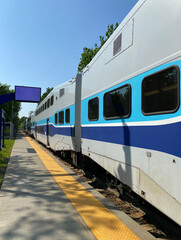 Fototapeta premium City train at the station ready for departure. Close up of wagons and windows of a suburban train at the boarding platform. Display panel for travel times.